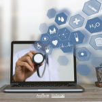 Computer portatile su una scrivania che mostra sullo schermo la mano di un medico con uno stetoscopio e icone digitali a tema medico-sanitario.