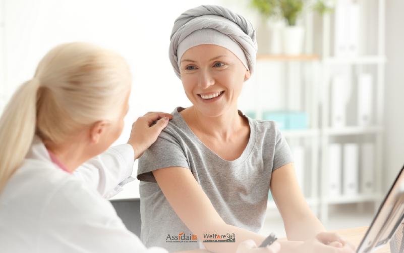 Medico che offre supporto e conforta una paziente sorridente con copricapo in studio, simbolo di cura e ricerca oncologica.