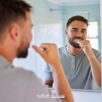 Uomo si lava i denti davanti allo specchio del bagno, immagine sul tema della salute orale