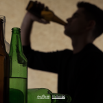 Persona beve alcol da una bottiglia con diverse bottiglie vuote in primo piano